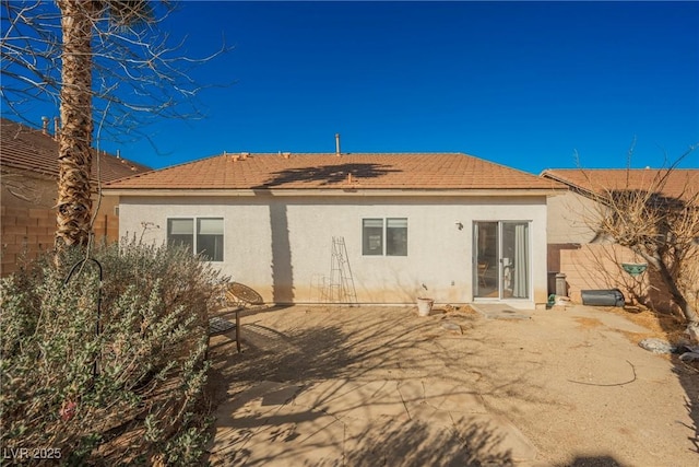 rear view of house featuring a patio, fence, and stucco siding