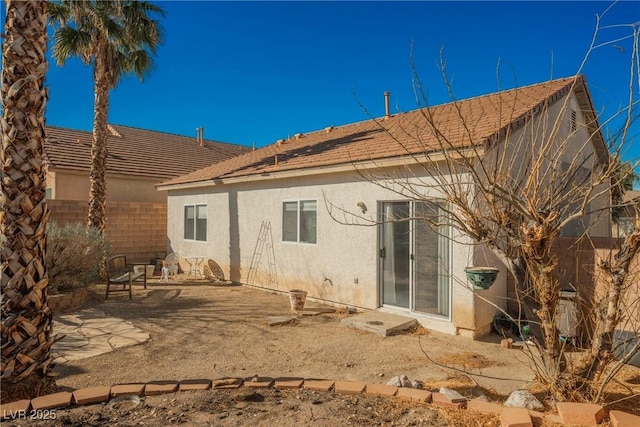 rear view of property featuring a patio area, fence, and stucco siding