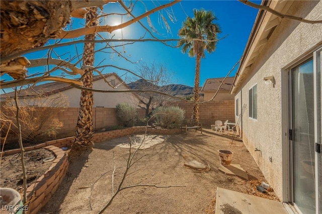 view of yard featuring a fenced backyard, a mountain view, and a patio