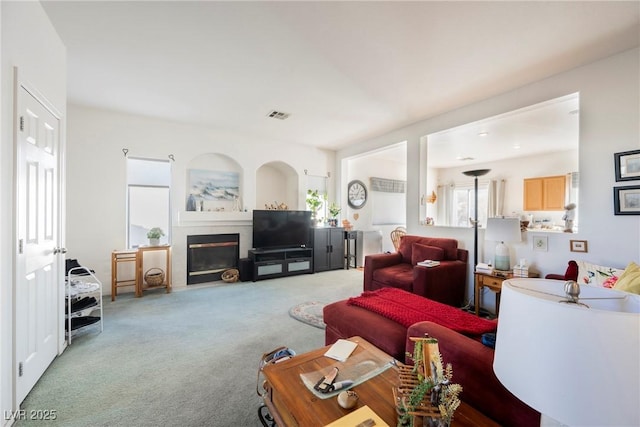 carpeted living room featuring visible vents and a glass covered fireplace