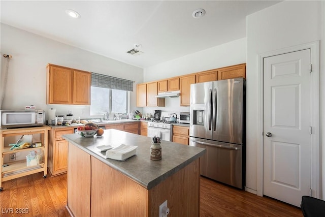 kitchen with white appliances, wood finished floors, visible vents, and under cabinet range hood