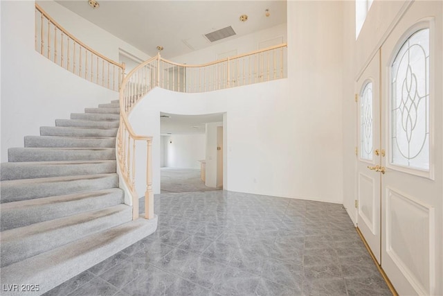 entryway with a high ceiling, visible vents, french doors, stairway, and carpet