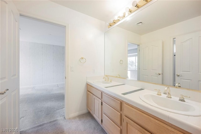 bathroom with visible vents, a sink, baseboards, and double vanity