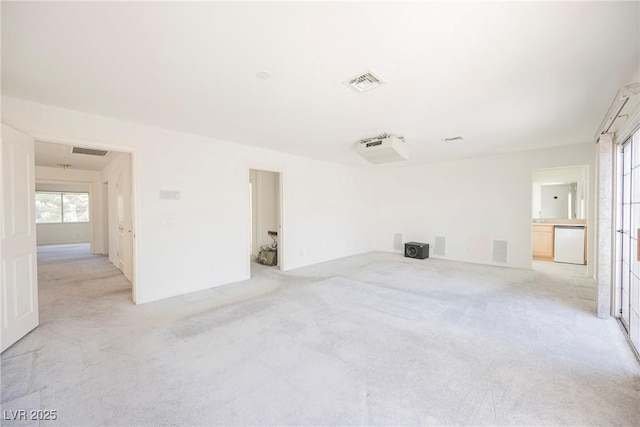 unfurnished room with visible vents and light colored carpet