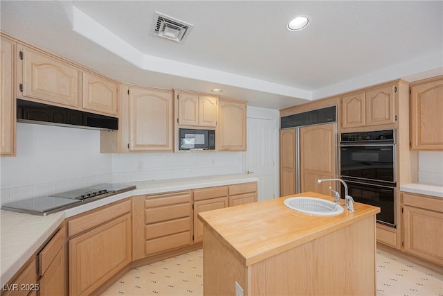 kitchen with light brown cabinetry, black appliances, visible vents, and under cabinet range hood