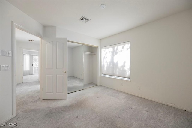 unfurnished bedroom featuring carpet floors, visible vents, and multiple windows