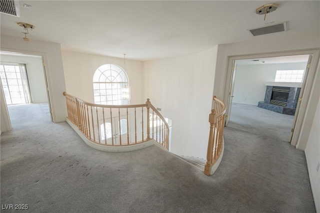 hall with visible vents, carpet flooring, and an upstairs landing