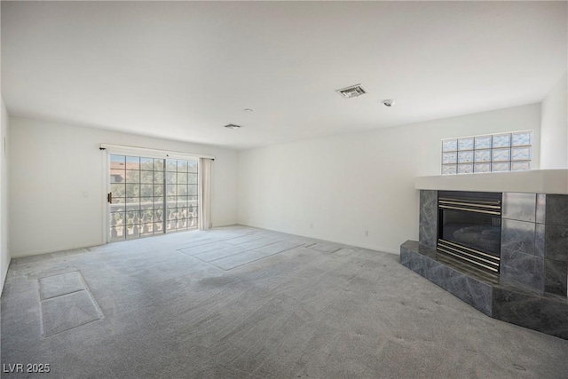 unfurnished living room with plenty of natural light, visible vents, a fireplace, and carpet flooring