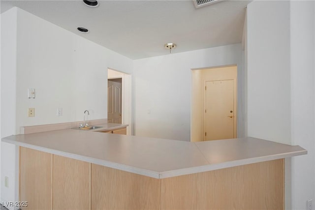 kitchen with a peninsula, a sink, and light countertops