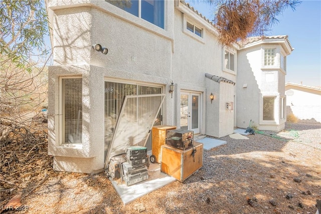 back of property featuring a tiled roof and stucco siding