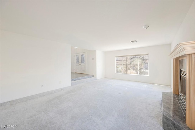 unfurnished living room featuring carpet floors and a fireplace with raised hearth