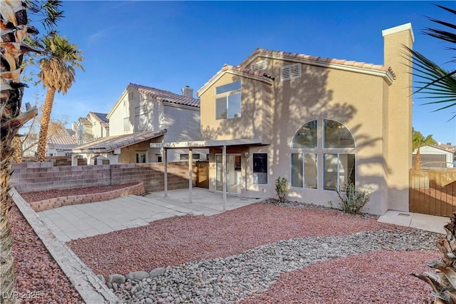 back of property featuring a patio area, a chimney, fence, and stucco siding