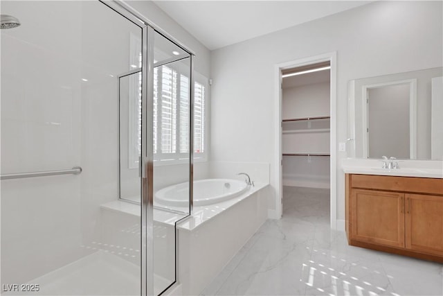 bathroom featuring vanity, marble finish floor, a shower stall, a bath, and a walk in closet