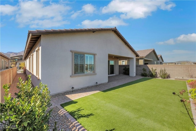 back of house with a patio area, a fenced backyard, a yard, and stucco siding