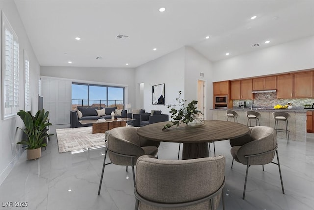 dining space featuring recessed lighting, marble finish floor, visible vents, and a high ceiling