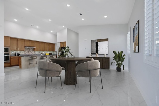 dining space featuring marble finish floor, recessed lighting, visible vents, a towering ceiling, and baseboards