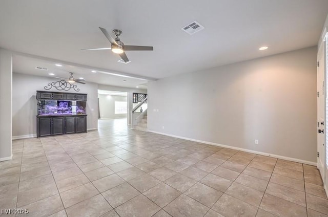 unfurnished living room with baseboards, visible vents, a ceiling fan, stairway, and light tile patterned flooring