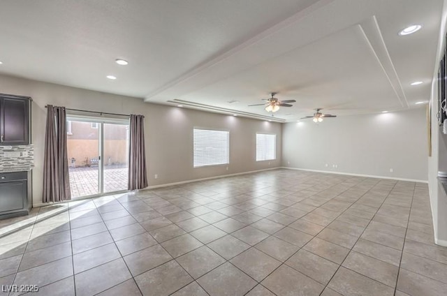 unfurnished living room featuring a wealth of natural light, light tile patterned flooring, ceiling fan, and baseboards