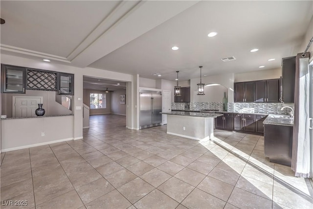 kitchen featuring light tile patterned floors, tasteful backsplash, visible vents, and stainless steel built in refrigerator