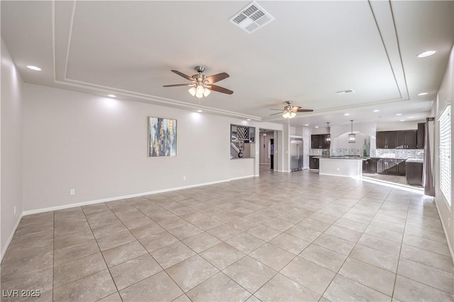 unfurnished living room with baseboards, a tray ceiling, visible vents, and recessed lighting