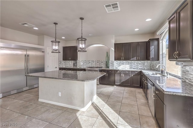 kitchen featuring stainless steel appliances, visible vents, a sink, and dark brown cabinets