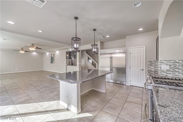 kitchen featuring light tile patterned floors, stainless steel appliances, a kitchen island, visible vents, and tasteful backsplash