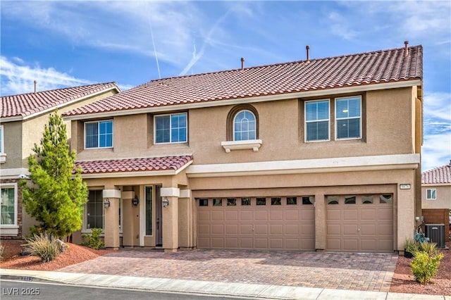 view of front facade with a garage, central AC, decorative driveway, and stucco siding