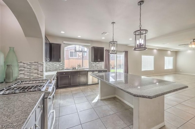 kitchen featuring a kitchen island, open floor plan, light stone countertops, stainless steel appliances, and light tile patterned flooring