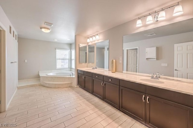 full bath featuring double vanity, a garden tub, visible vents, and wood tiled floor