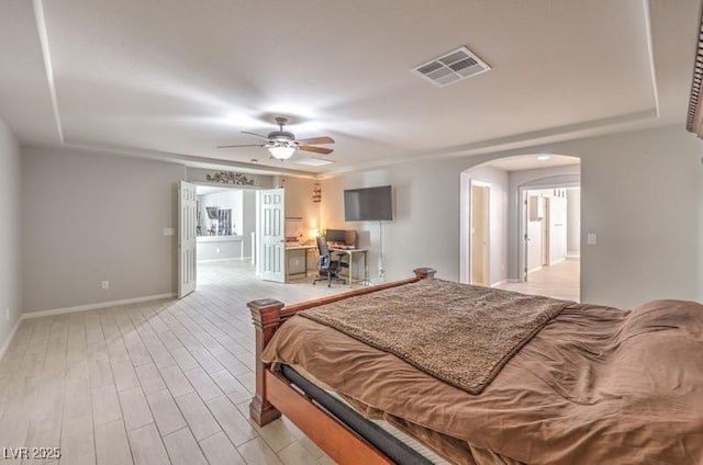 bedroom featuring arched walkways, wood finished floors, a ceiling fan, visible vents, and baseboards