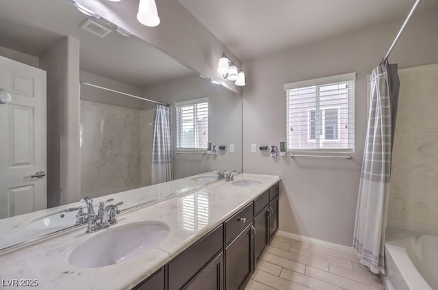 bathroom with double vanity, visible vents, baseboards, and a sink