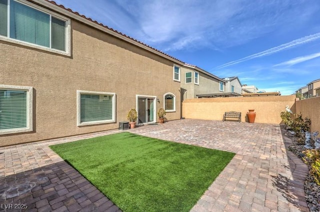 back of house with a patio, a yard, fence, and stucco siding