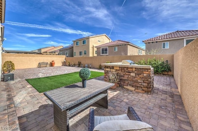 view of patio with exterior kitchen and a fenced backyard