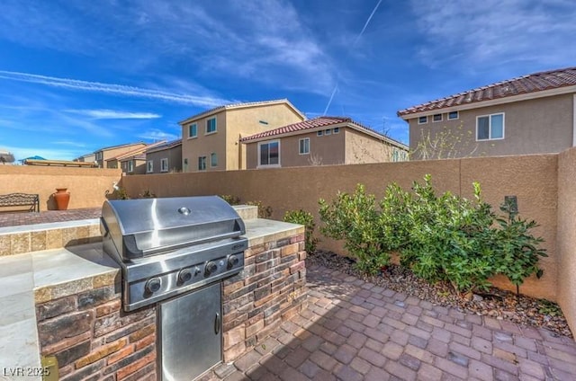 view of patio featuring exterior kitchen, a fenced backyard, and grilling area