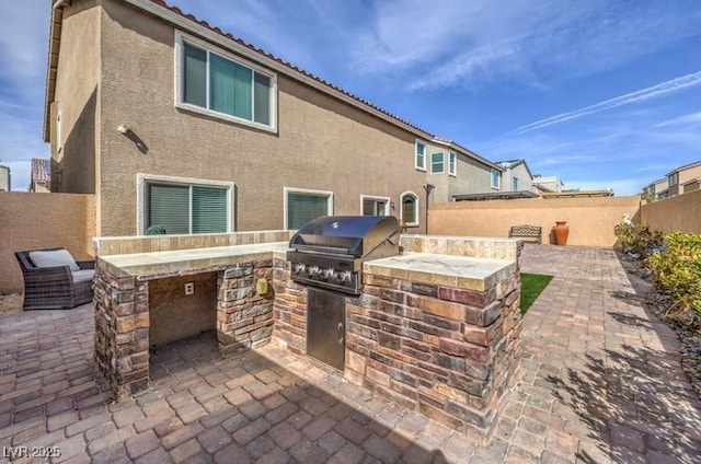 view of patio / terrace with exterior kitchen, area for grilling, and a fenced backyard