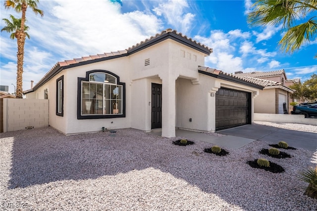 mediterranean / spanish-style house featuring concrete driveway, an attached garage, fence, and stucco siding