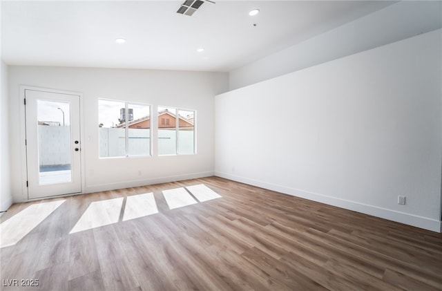 unfurnished room featuring visible vents, baseboards, wood finished floors, and vaulted ceiling