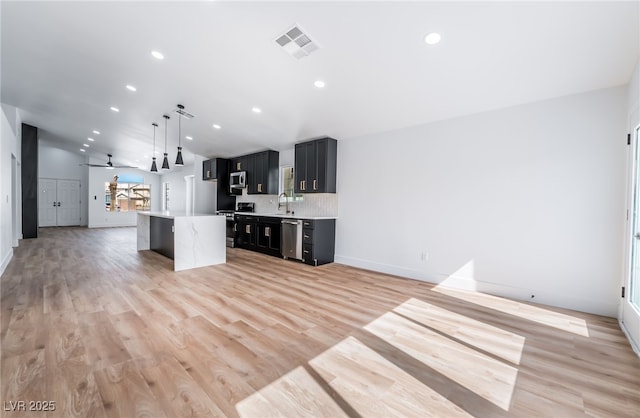 kitchen with visible vents, open floor plan, light countertops, dark cabinetry, and stainless steel appliances