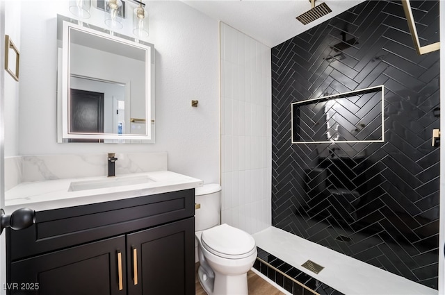 bathroom with vanity, toilet, and a tile shower