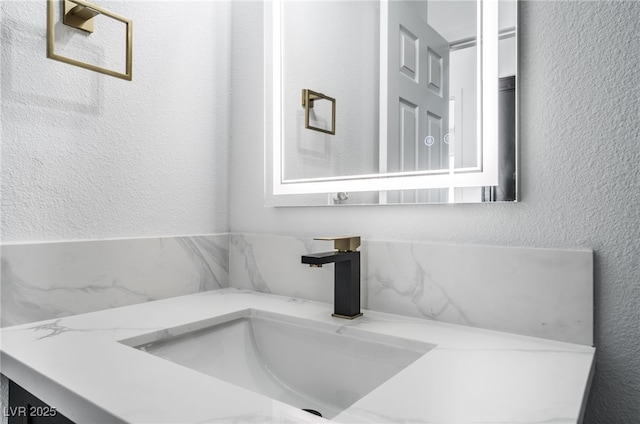 bathroom featuring a sink and a textured wall