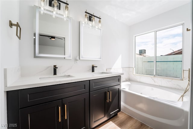 full bathroom featuring double vanity, a whirlpool tub, wood finished floors, and a sink