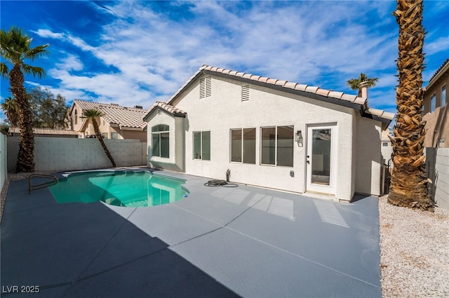 rear view of property with stucco siding, a tile roof, a fenced backyard, and a patio area