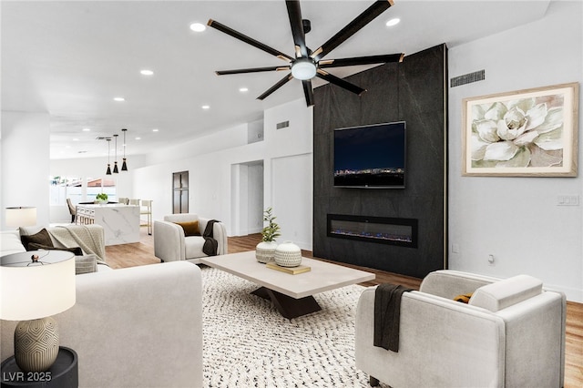 living room with recessed lighting, visible vents, wood finished floors, and a fireplace