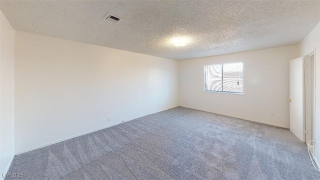 carpeted spare room with visible vents and a textured ceiling