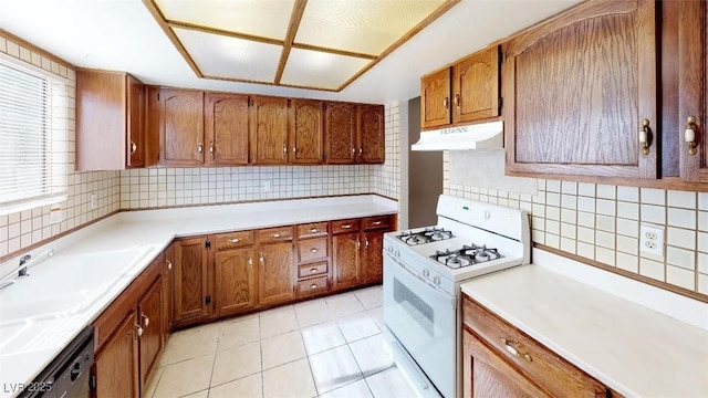 kitchen featuring gas range gas stove, under cabinet range hood, black dishwasher, light tile patterned floors, and brown cabinets