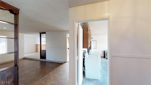 corridor with separate washer and dryer and a textured ceiling