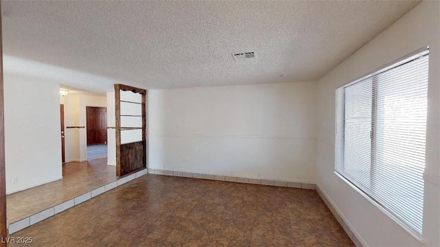 unfurnished room with visible vents, baseboards, and a textured ceiling