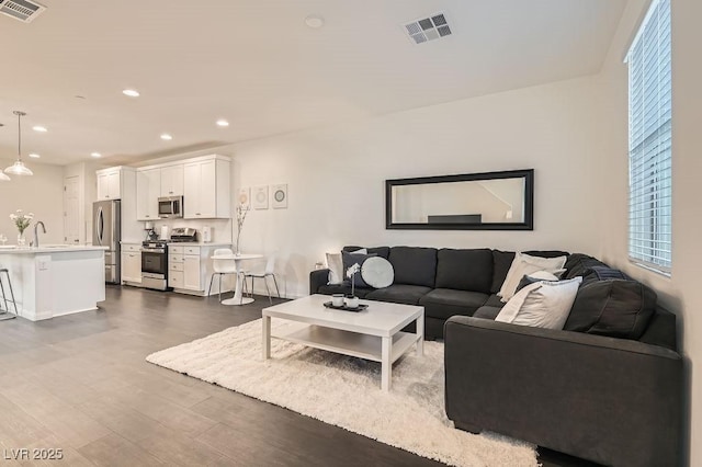 living area with recessed lighting, dark wood-style flooring, and visible vents