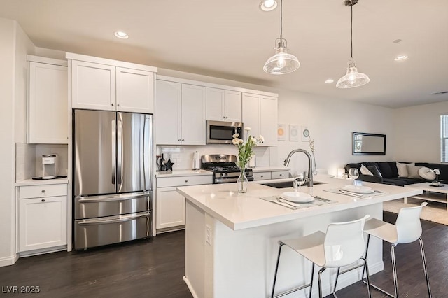 kitchen featuring stainless steel appliances, a sink, white cabinetry, light countertops, and dark wood-style floors