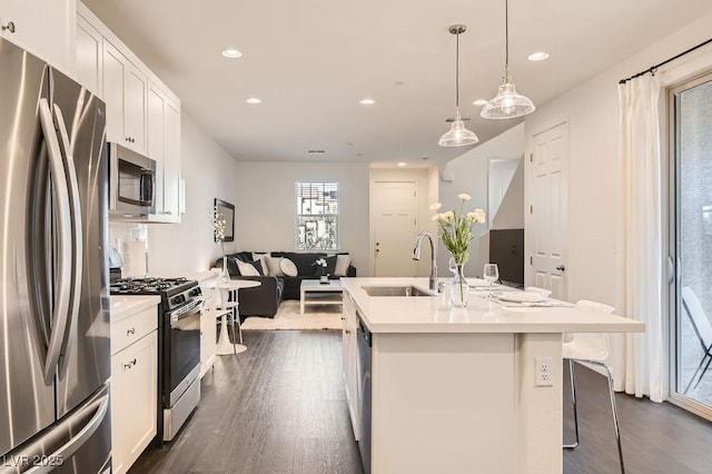 kitchen featuring dark wood-style flooring, stainless steel appliances, light countertops, white cabinetry, and a sink